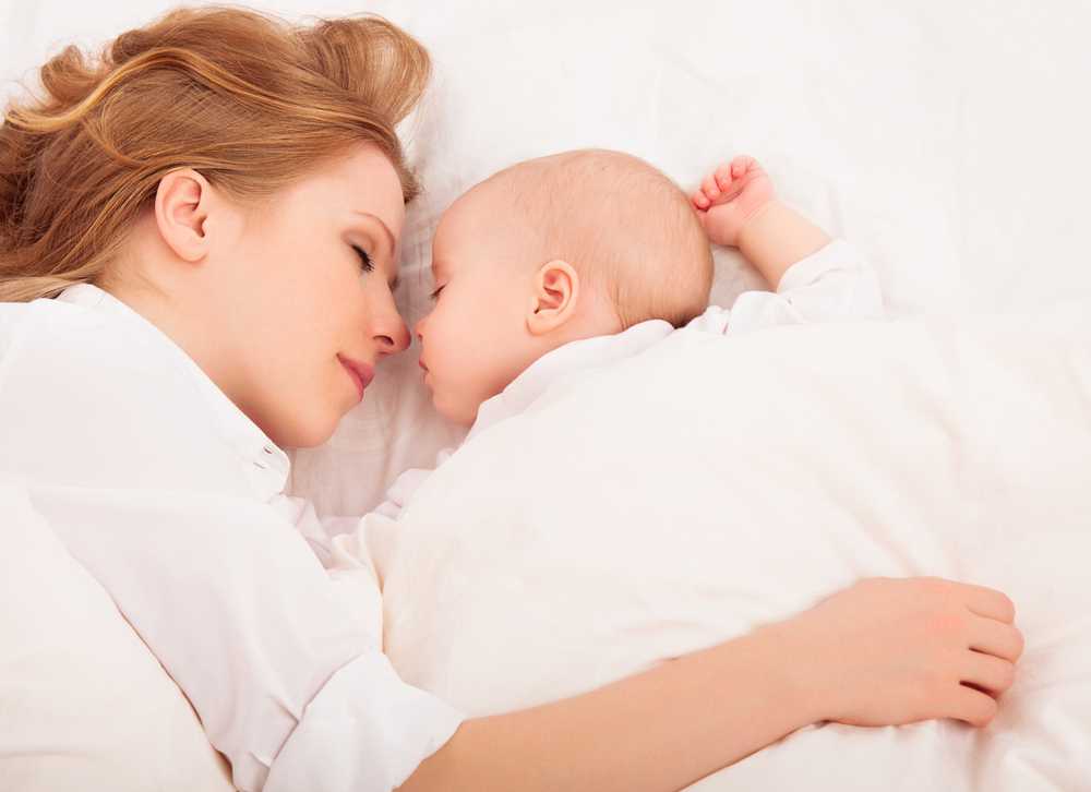 sleep without sleep training - mom with her arm over baby while sleeping in bed