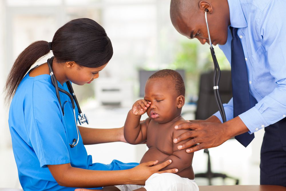 Doctor checking baby's lungs with stethoscope while nurse coos and talk to the baby