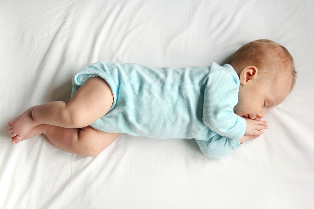 A precious newborn infant is laying on a comfortable white bed, sleeping peacefully