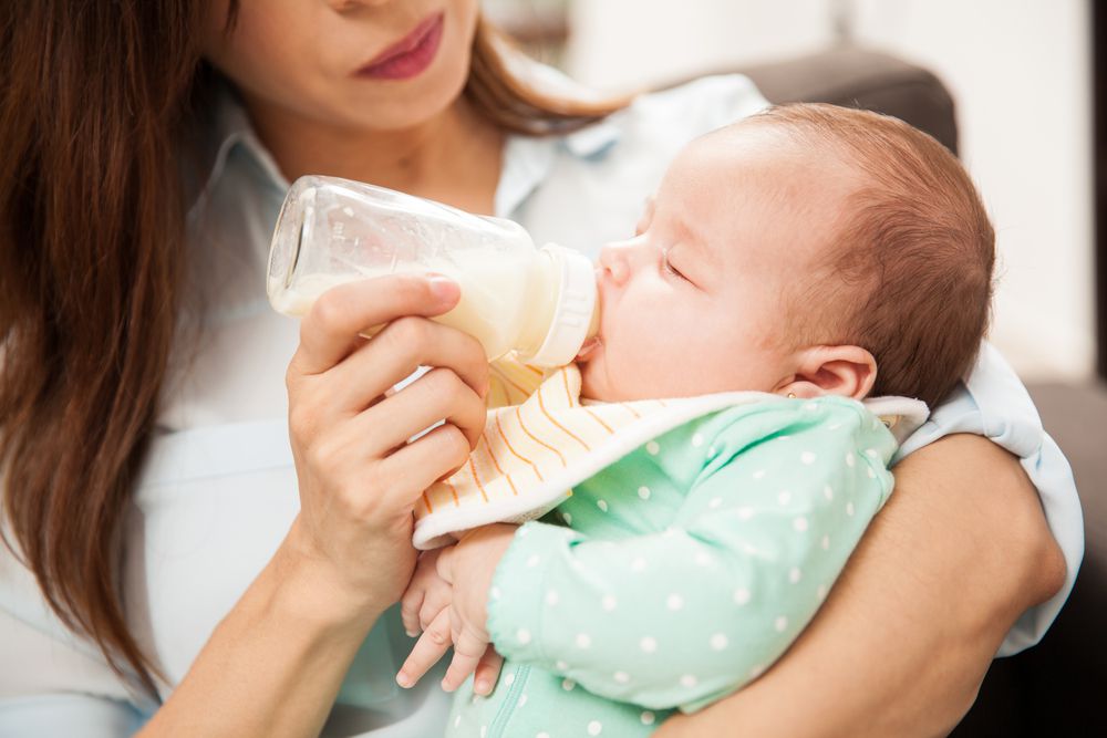 mom holding baby in her arms and feeding baby a bottle