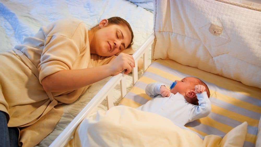 Mom laying next to baby in crib while doing gentle sleep training