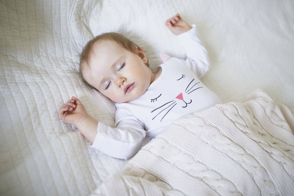 Baby sleeping independently in crib with cat pajamas